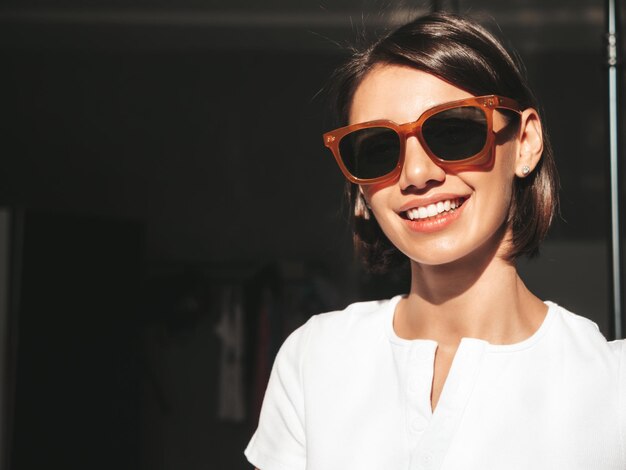 Closeup portrait of young beautiful smiling female Sexy carefree woman posing at sunny day on dark background Positive model having fun and going crazy Cheerful and happy In sunglasses