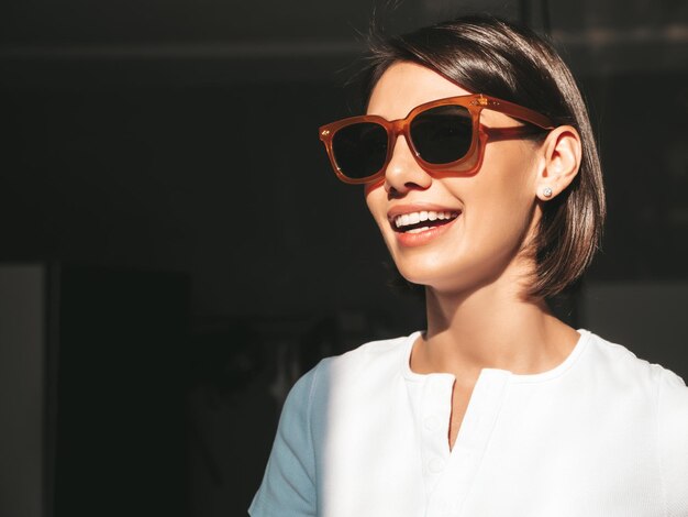 Closeup portrait of young beautiful smiling female Sexy carefree woman posing at sunny day on dark background Positive model having fun and going crazy Cheerful and happy In sunglasses