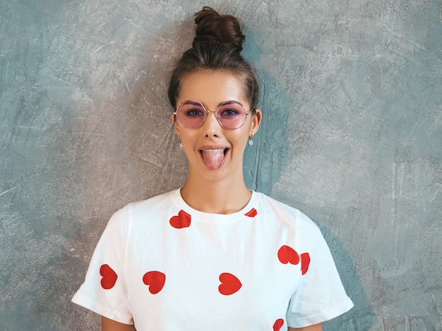 Free photo closeup portrait of young beautiful smiling woman looking . trendy girl in casual summer white dress and sunglasses. . show her tongue