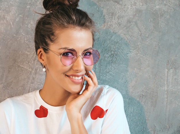 Foto gratuita ritratto del primo piano di giovane bello sguardo sorridente della donna. ragazza alla moda in abito bianco estivo casual e occhiali da sole.