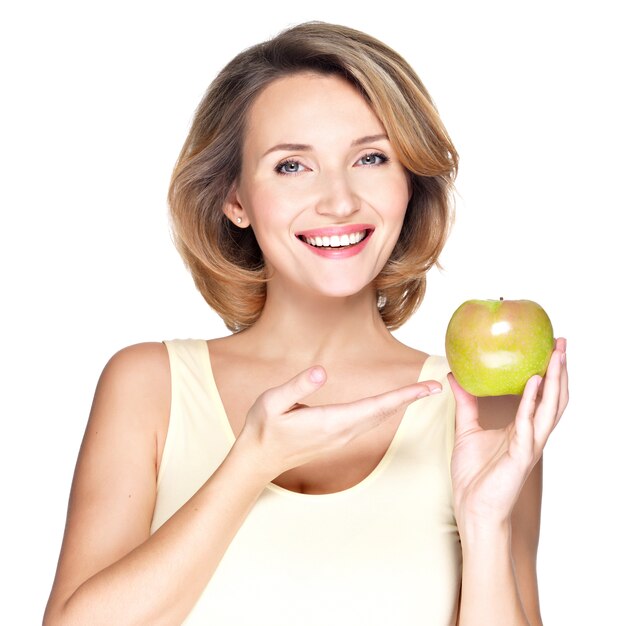Крупным планом портрет молодой красивой улыбающейся женщины, указывая на яблоко - изолированное на белом.
