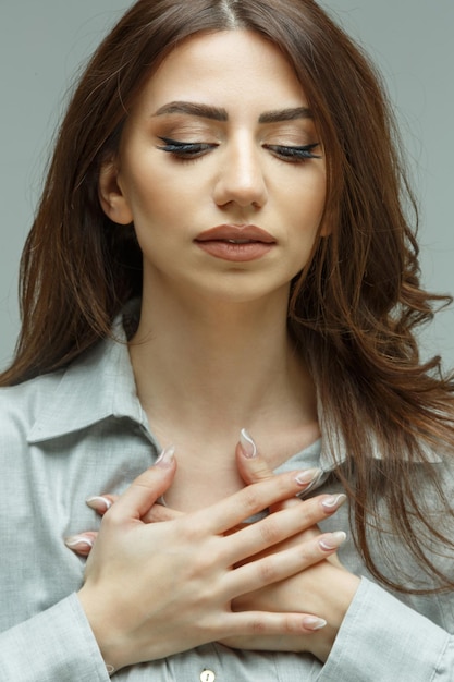 Foto gratuita closeup ritratto di giovane ragazza mettere le mani al petto e guardare in basso foto di alta qualità