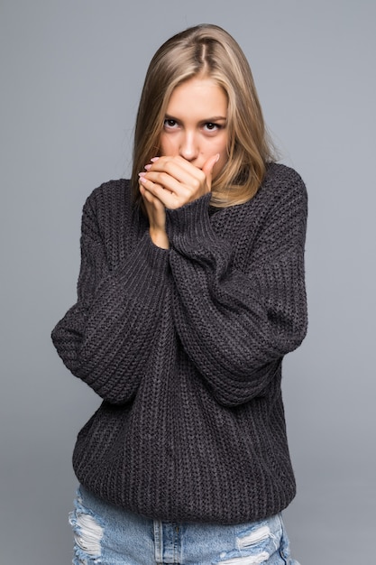 Closeup portrait of a young happy woman in warm winter outfit on gray background