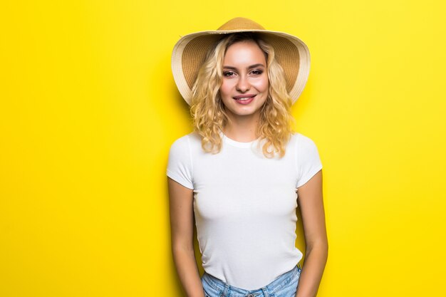 Портрет крупным планом молодой красивой женщины в короткой соломенной шляпе на желтой стене