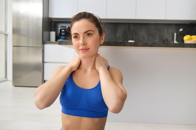 Foto gratuita ritratto in primo piano di una donna in forma fisica che si allena a casa massaggiando l'esercizio del collo nel vivo
