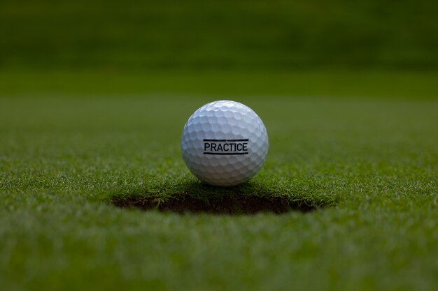 Closeup of a practice text written on a golf ball on the lawn under the sunlight