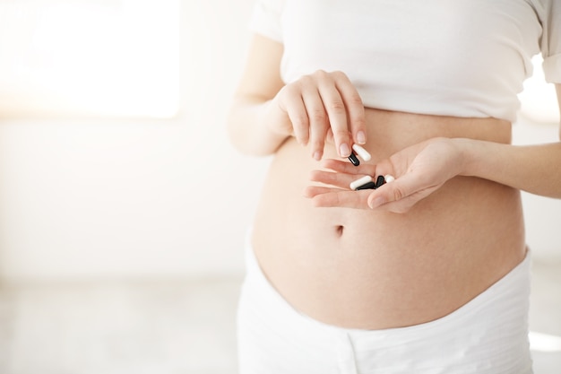 すぐに妊娠中のクローズアップは、錠剤や薬やビタミンを保持している母親になります。健康な母性の概念。
