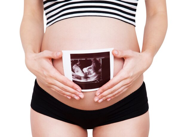 Closeup pregnant woman holding ultrasound image