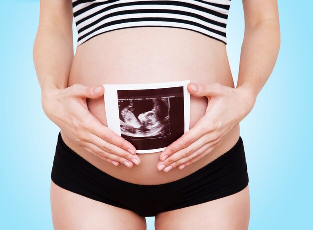 Closeup pregnant woman holding ultrasound image