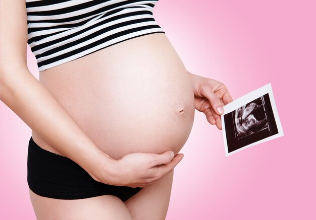 Closeup pregnant woman holding ultrasound image