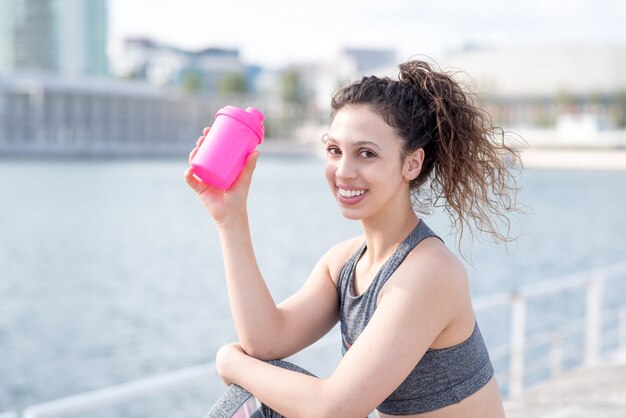 Closeup of Pretty Sporty Girl Drinking by City River