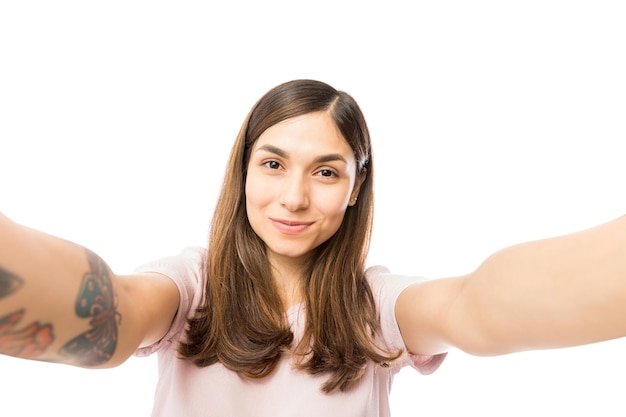 Closeup of pretty young female taking selfie and smiling over white background