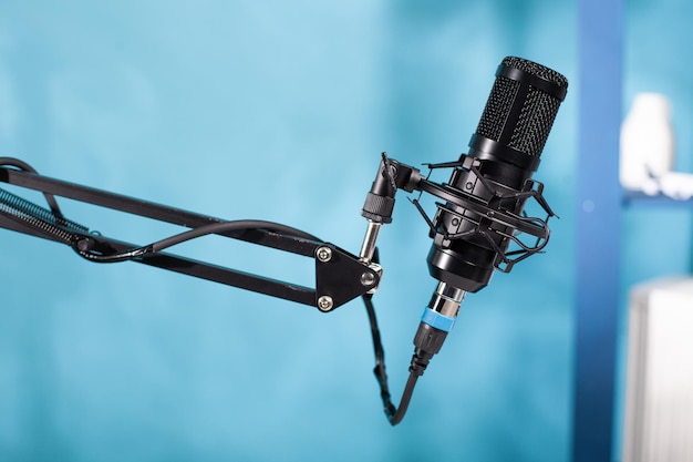 Closeup of professional microphone swivel boom arm stand in empty vlog broadcasting studio used for recording social media content. Detail of audio live broadcast digital mic.