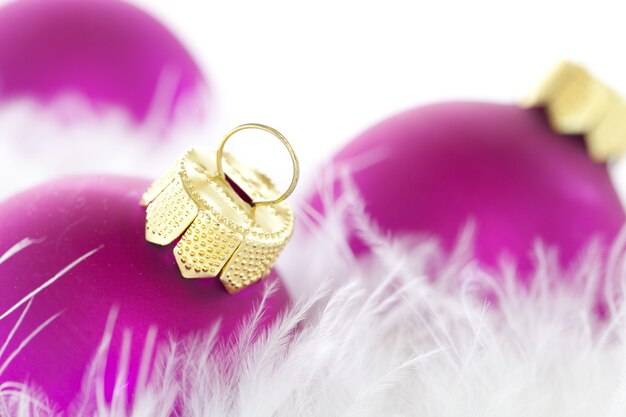 Closeup of purple Christmas ornaments and feathers under the lights with a blurry background