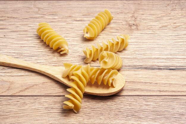 Closeup of raw fusilli with a wooden spoon on the table