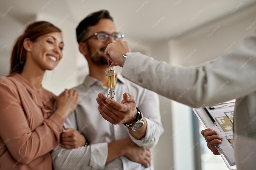 Person handing over a key to another, with a clipboard showing a floor plan.
