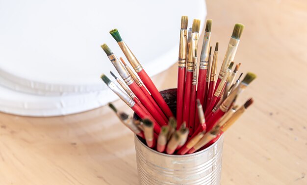 Closeup of red paint brushes in a metal jar