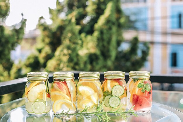 Closeup of refreshing drinks with fruits in a jar on the table under the sunlight