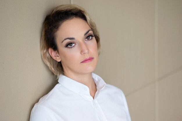 Closeup of Relaxed Serious Woman Leaning on Wall