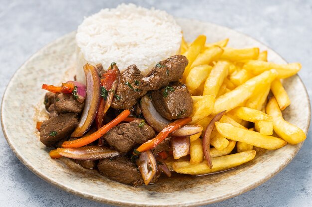 Closeup of roasted meat with sauce, vegetables and fries in a plate on the table