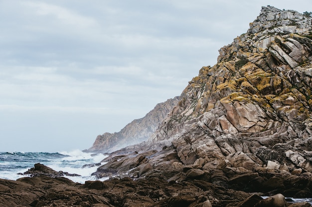 Foto gratuita primo piano delle rocce circondate dal mare sotto un cielo nuvoloso durante il giorno