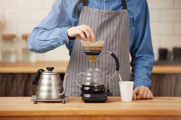 Крупный план rofessional бармена подготавливая кофе piton в chemex.