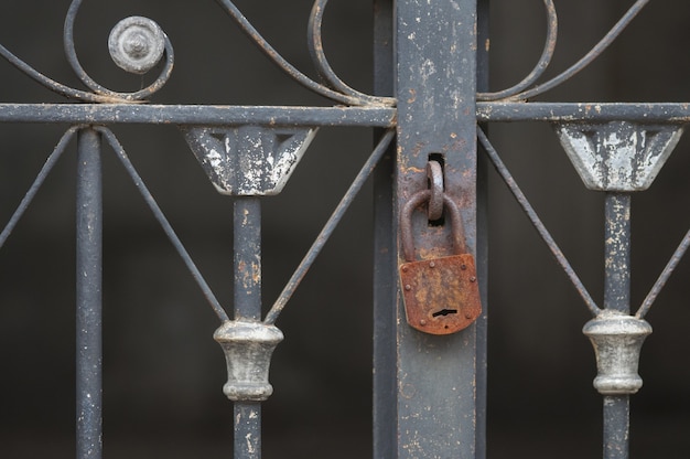 Closeup of a rusty padlock on an old metallic fence in a graveyard