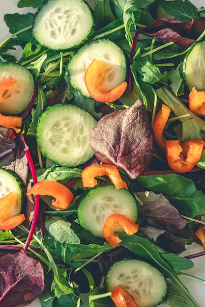 Closeup salad with fresh cucumbers peppers and arugula