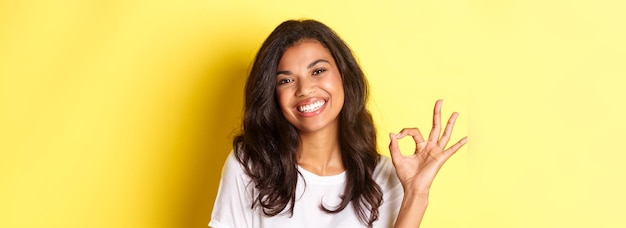 Free photo closeup of satisfied africanamerican woman showing okay sign and smiling recommending something good