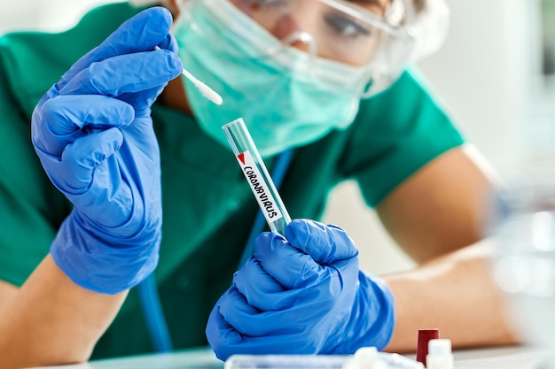 Крупный план ученого, изучающего образец теста на коронавирус в лаборатории