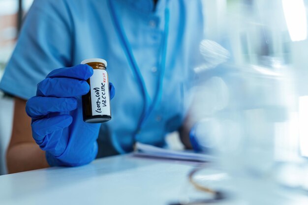 Closeup of scientist holding coronavirus vaccine in test tube while working on medical research in laboratory