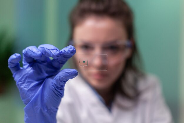 Крупный план женщины-ученого, смотрящей на тестовый образец листа, анализирующий для биологического эксперимента с органическими растениями