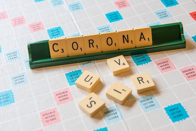 Free photo closeup of a scramble board with the words corona and virus on it under the lights