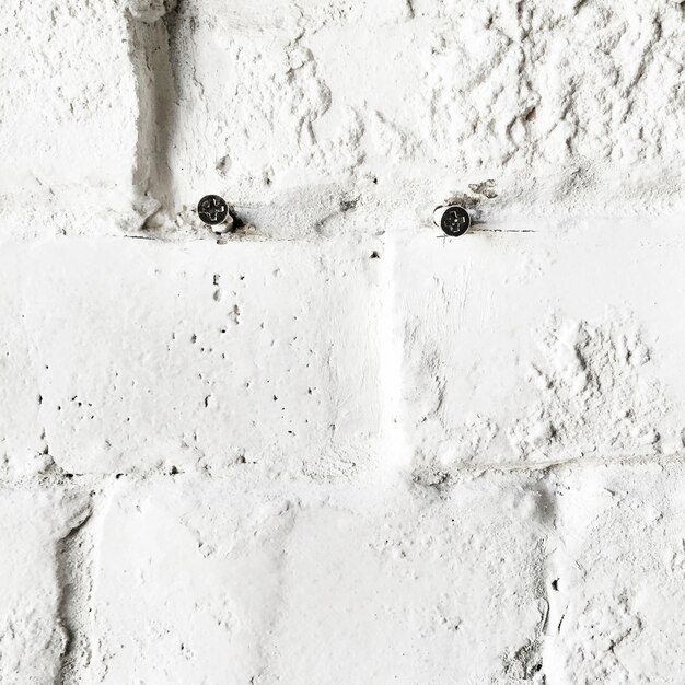 Closeup of screws on concrete white brick wall