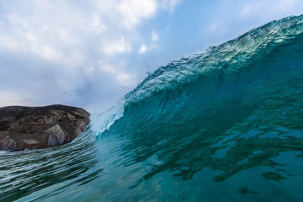 Closeup of a sea wave with rocks under a cloudy sky in Algarve, Portugal