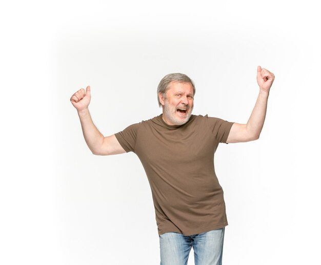白で隔離される空の茶色のtシャツで年配の男性の体のクローズアップ。