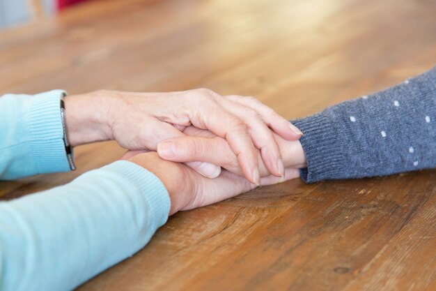 Closeup of senior woman holding daughters hand