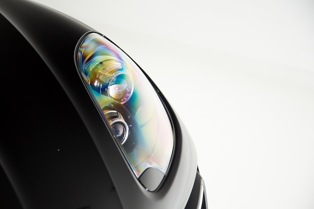 Closeup of the shiny headlight of a black luxury car isolated on a white background