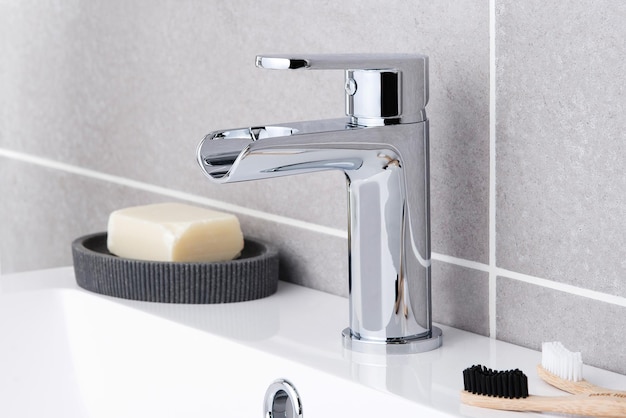 Closeup of a shiny modern faucet soap and toothbrushes