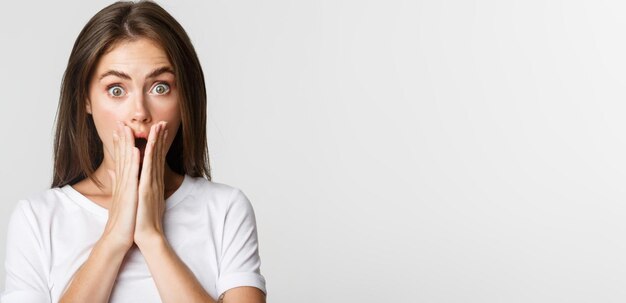 Closeup of shocked gasping brunette girl cover mouth with hands surprised