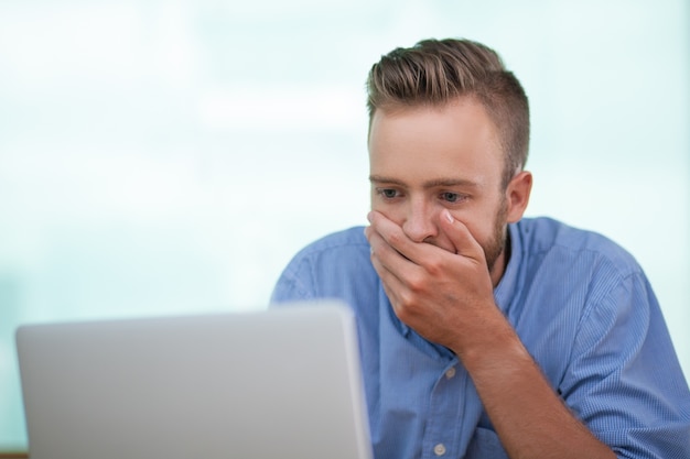 Closeup of Shocked Young Man Working on Laptop