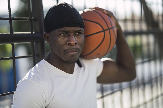 Closeup shot of an African-American male in a white shirt carrying the ball on his shoulder