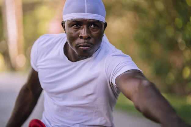 Closeup shot of an African-American male in a white shirt stretching at the park