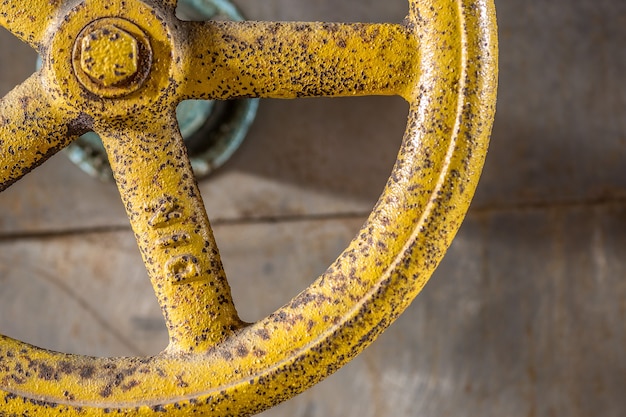 Closeup shot of an antique yellow steel wheel attached on a wall