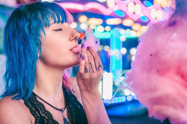 Closeup shot of an attractive young female enjoying eating cotton candy in an amusement park