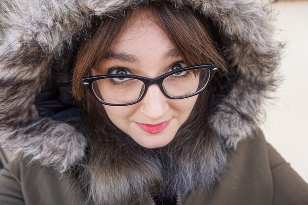 Closeup shot of a beautiful girl with glasses wearing a coat in winter day