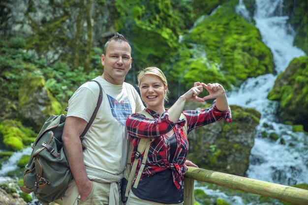 Closeup shot of a beautiful loving couple in nature with a waterfall on the distance