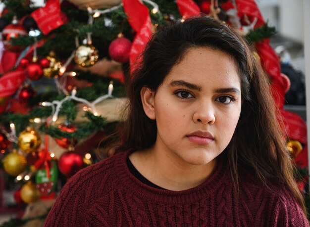 Closeup shot of a beautiful young lady in front of a Christmas tree