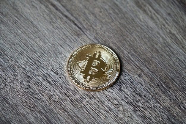 Foto gratuita colpo del primo piano di un bitcoin su un tavolo di legno