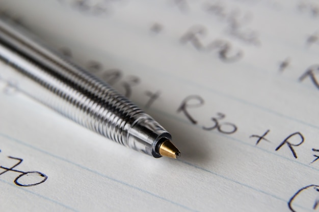 Free photo closeup shot of a black pen on a piece of paper with some numbers and codes written on it